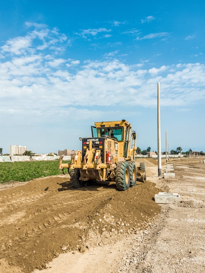 A powerful tractor working on a construction site under a bright blue sky, highlighting heavy engineering equipment.